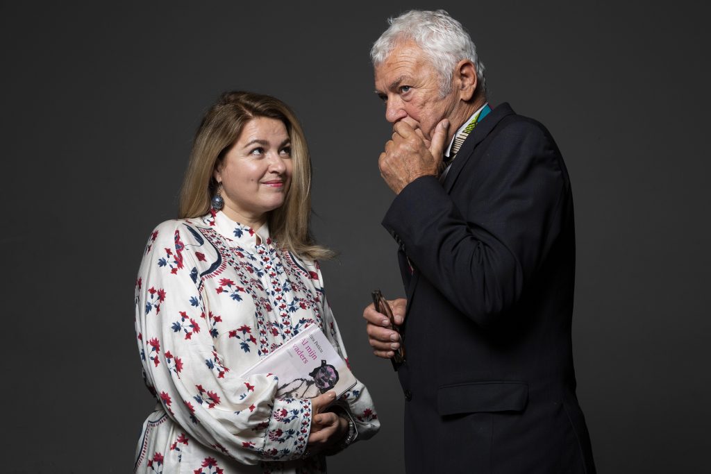 Twee personen die tegenover elkaar staan, een van hen houdt een boek vast waar de voorstelling op gebaseerd is.